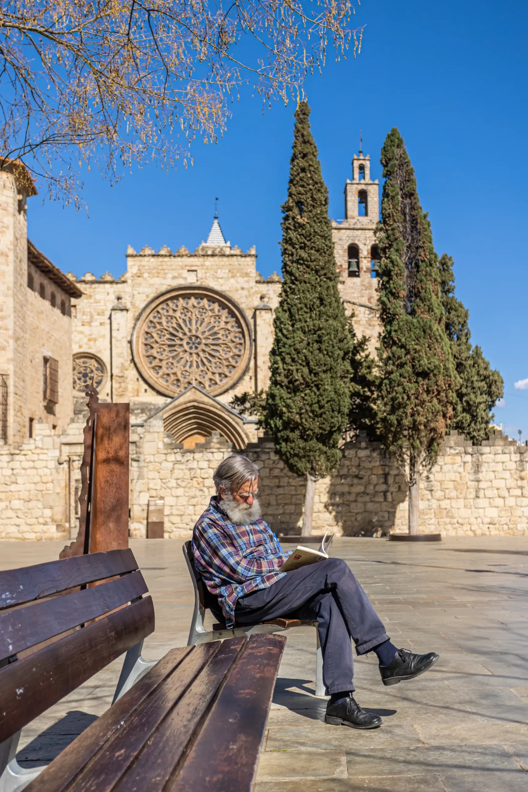 A Sant Cugat citizen reading a book in the morning with the iconic Iglesia del Monasterio behind