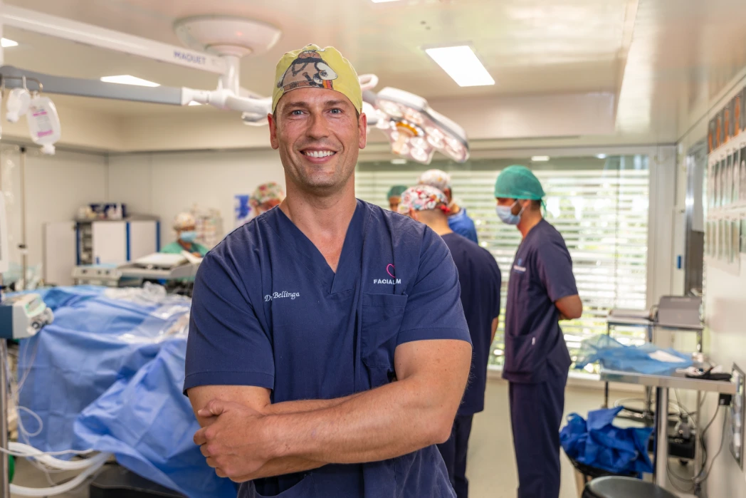 Aesthetic Surgery Director Dr. Raúl Bellinga from Facialteam posing in front of the operating theater with a facial feminization surgery in the back.