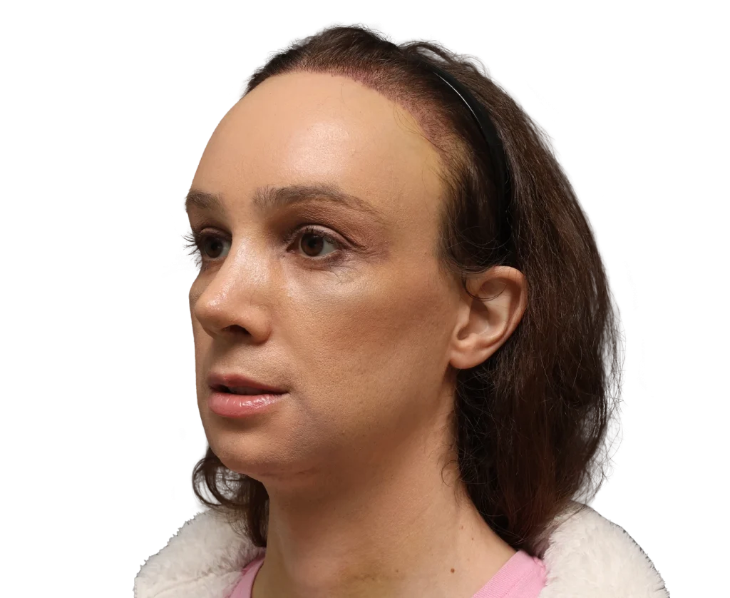 Close-up profile of a woman facing left, wearing a black headband and pink top with a white fleece jacket.