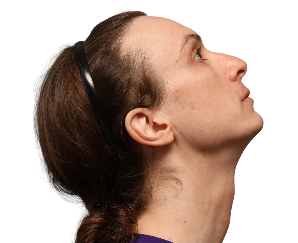 Side profile of a woman tilting her head upward, brown hair tied back, wearing black sunglasses on her head.