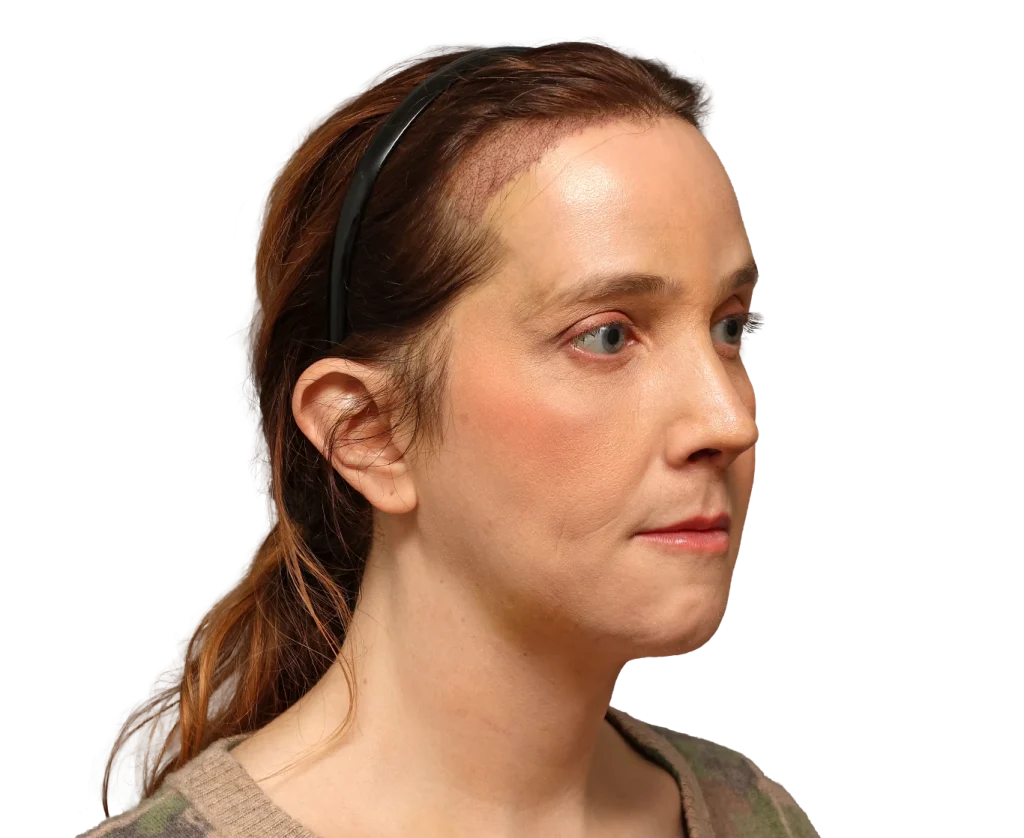 Side profile of a woman wearing a black headset, looking to the right with reddish-brown hair.