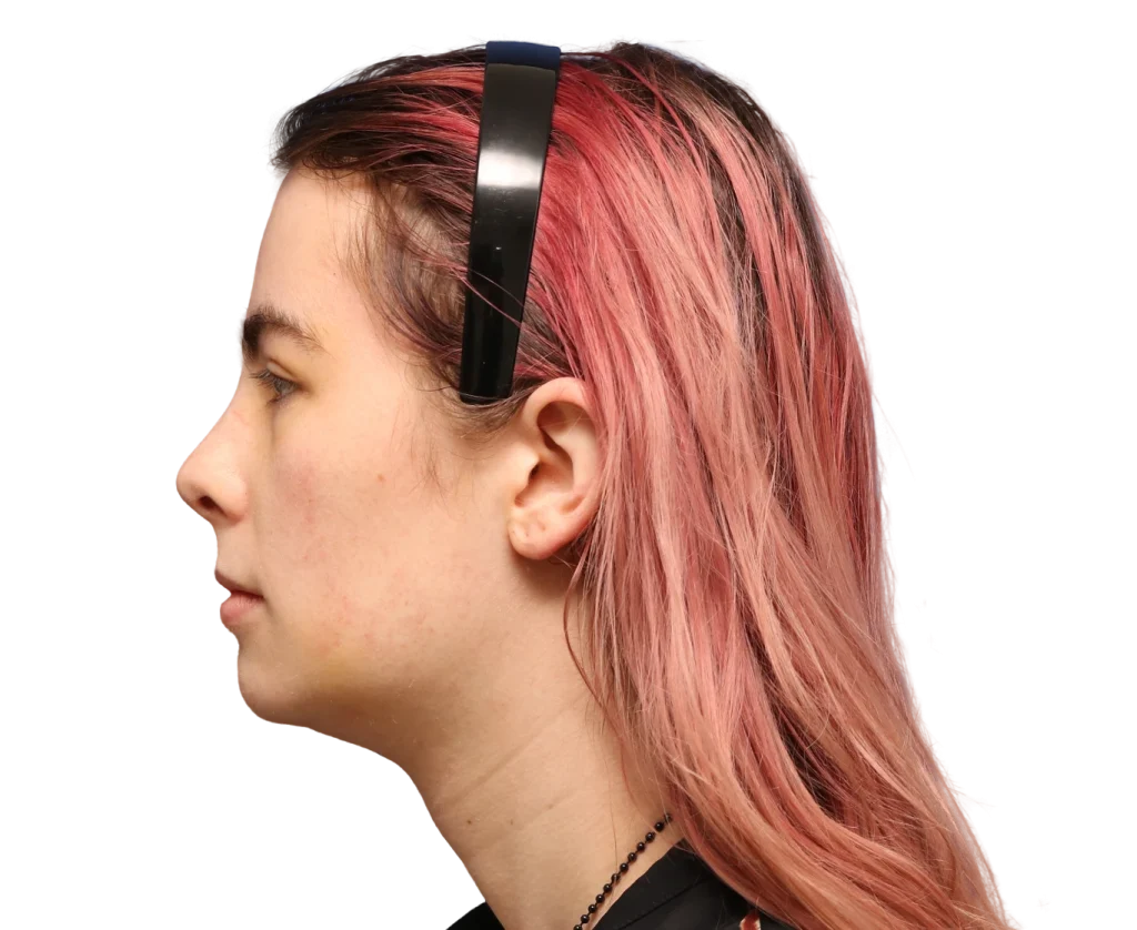 Side profile of Elléonore with pink-dyed hair wearing black headphones.