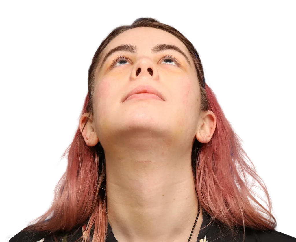 Close-up of Elléonore with pink-dyed hair looking upward, head tilted back.