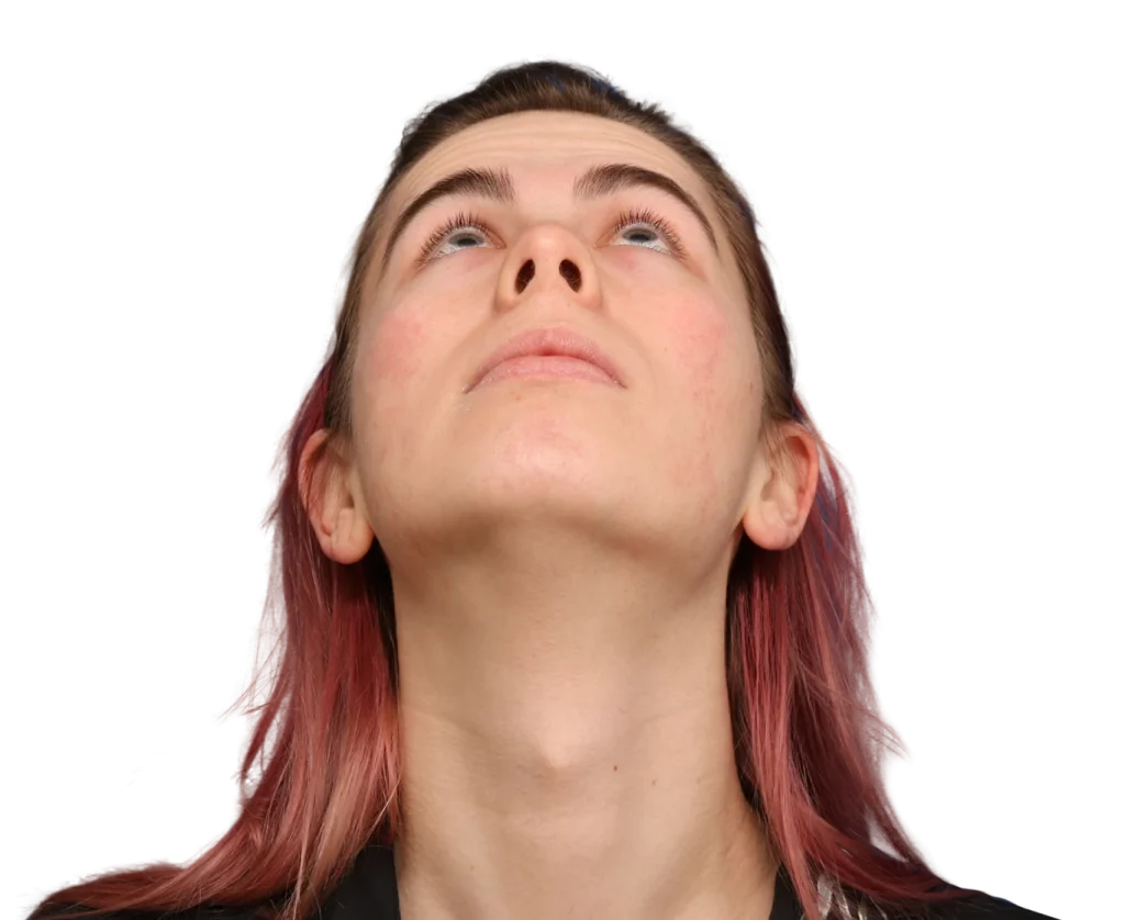 Close-up of Elléonore face looking upward, chin raised, with pink hair against a black background. (informative)