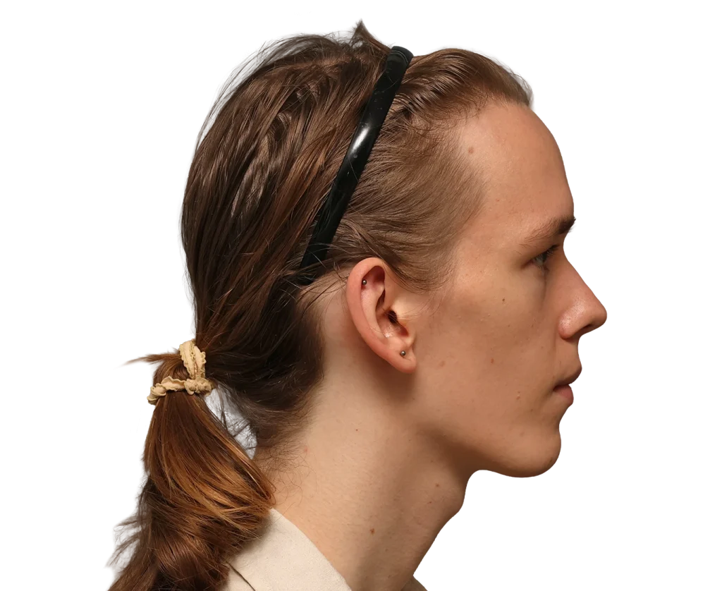 Profile of Zoey facing right, hair tied back with a beige scrunchie, black sunglasses on her head.