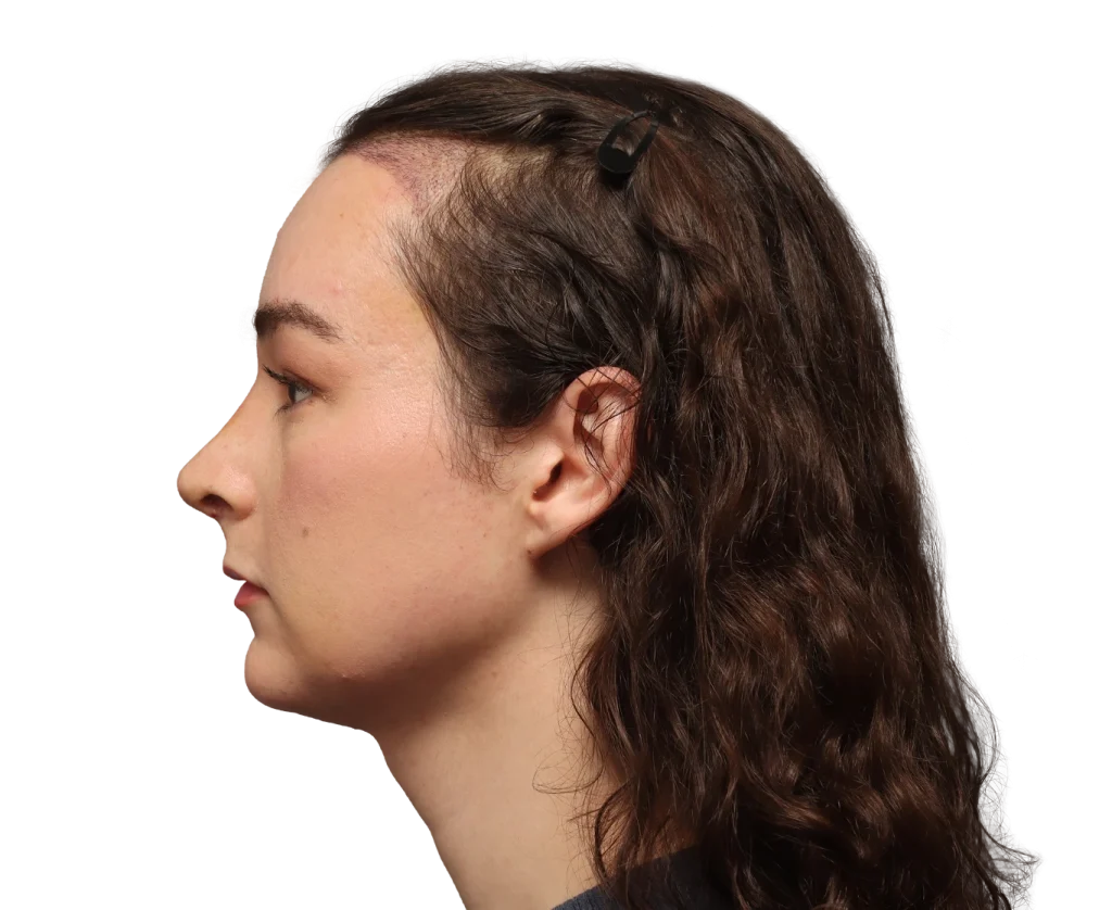 Profile view of a woman facing left with dark wavy hair clipped back by a small black hairpin
