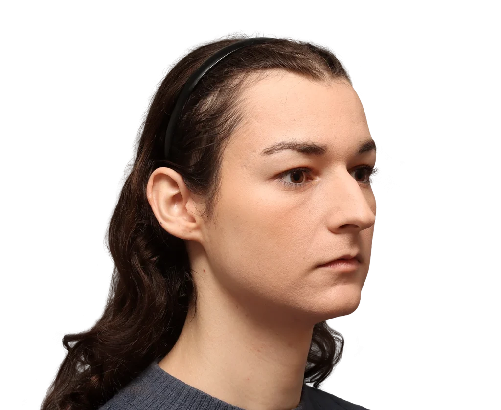 Profile view of a young woman with dark hair pulled back by a black headband, looking to the right, neutral expression.