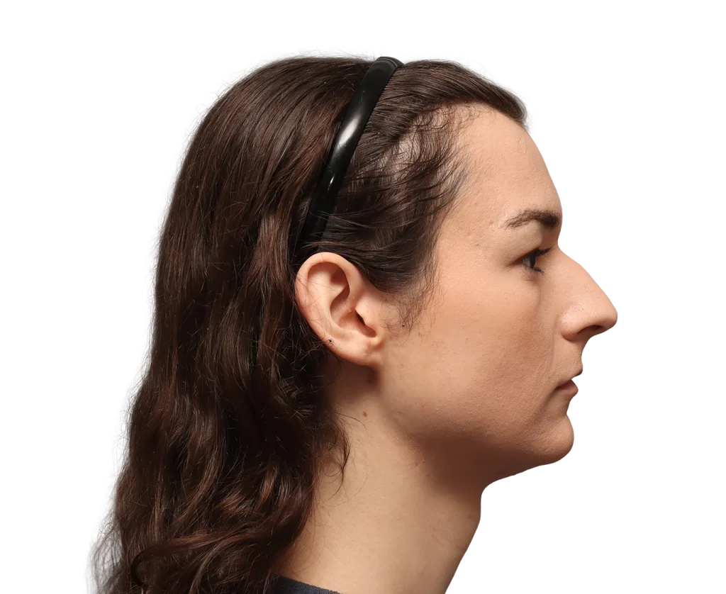 Profile view of a woman with long brown hair and a black headband, facing right against a black background. Angled side portrait.